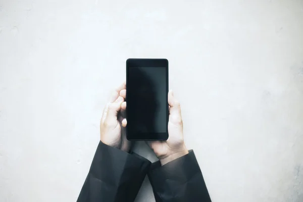 Hendene holder en blank svart smarttelefon – stockfoto