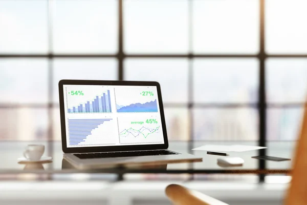 Ноутбук з фінансовою статистикою на скляному столі з чашкою ко — стокове фото