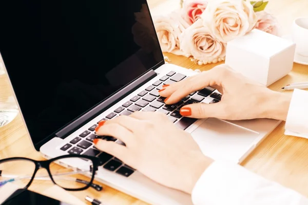 mulher de unhas vermelhas mexendo no teclado do notebook