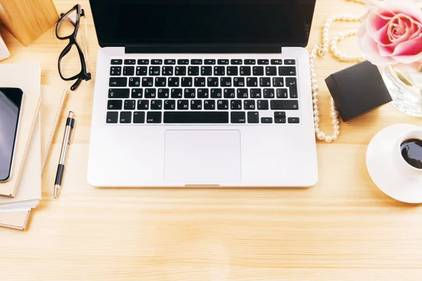 Vista superior do desktop designer feminino com flor, laptop, xícara de café, óculos e ferramentas de escritório — Fotografia de Stock