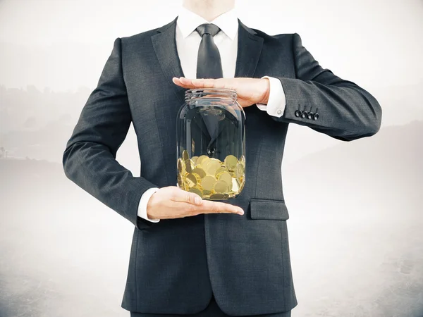 Hombre sosteniendo tarro con monedas — Foto de Stock