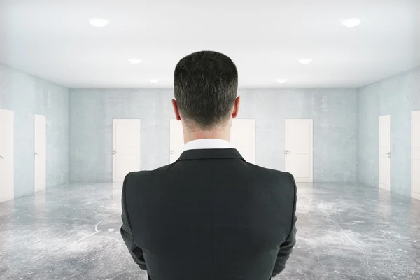 Thoughtful man in room with doors — Stock Photo, Image