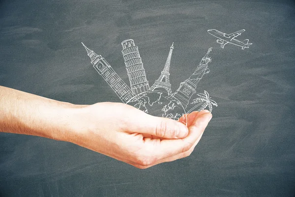 Male hand holding abstract sketch of landmarks and airplane on chalkboard background. Travel concept — Stock Photo, Image