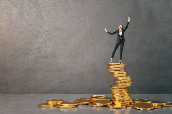 Businessman in suit standing on golden coins heap in gray concrete interior. Finance and success concept.