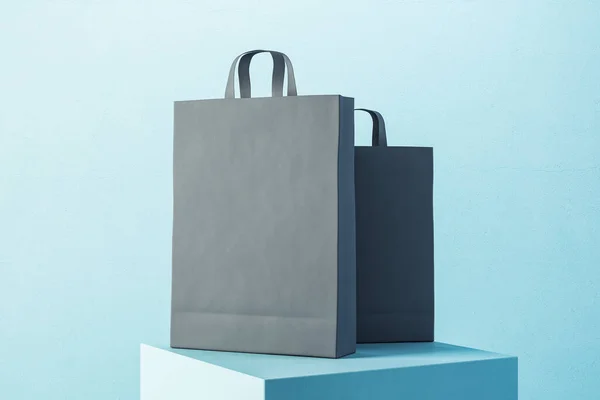 两个黑色纸制购物袋 手柄放在蓝色的讲台上 贸易和礼物概念 3D渲染 — 图库照片