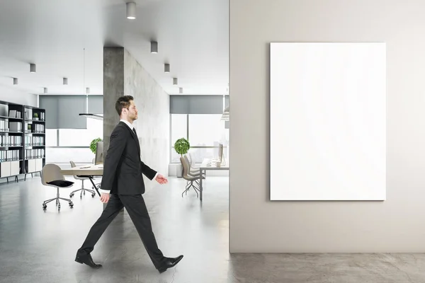 商人走在现代工作场所的内部与计算机和空白垂直海报墙上 工作场所和公司的概念 打起精神 — 图库照片