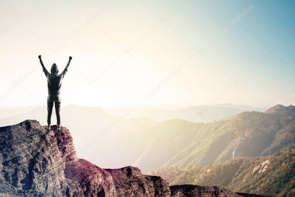 Happy hacker on cliff with clouds and copy space. Success and victory concept