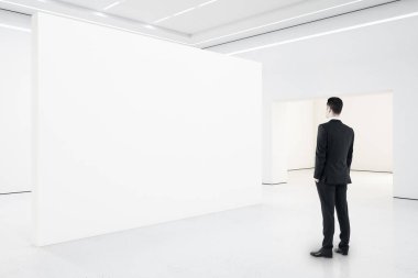 Minimalist galeri içinde iş adamı boş sunum duvarına bakıyor. Sanat ve tasarım konsepti. Model.