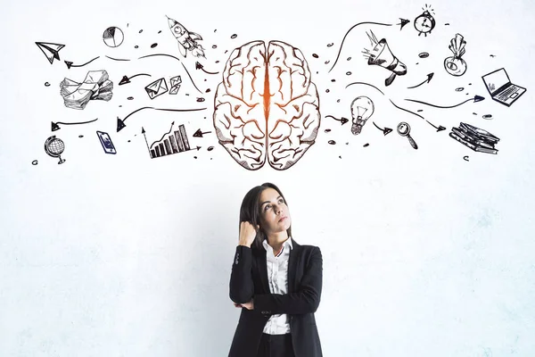 Left and right human brain concept with businesswoman on light wall background with painted sketch of business icons set