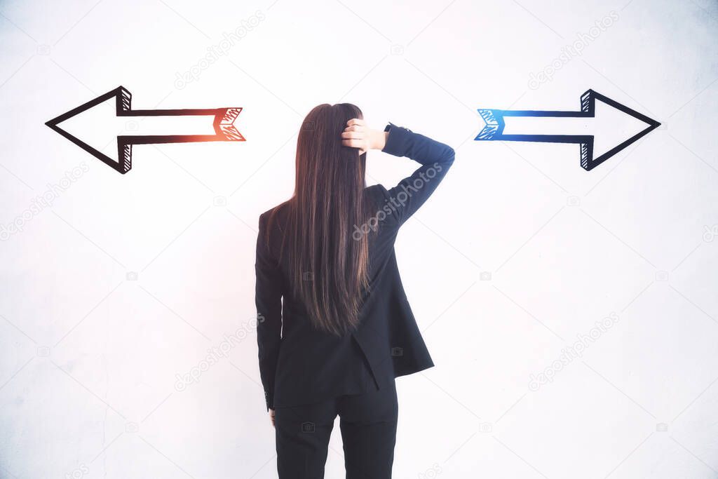 Businesswoman standing puzzled in front of a wall with two black silhouette arrows pointed in opposite directions, decision making and career pathway concept