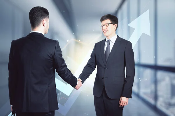 Business deal concept with businessmen handshaking on digital arrow background
