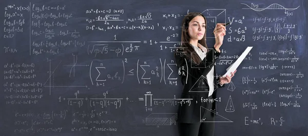 Studying process with young woman in black suit writing on transparent wall math calculations