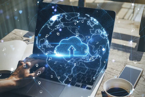 Global network and cloud storage concept with virtual cloud symbol in the Earth layout on human hand typing on laptop keyboard. Double exposure