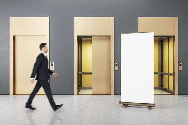 商人走在灰色混凝土的内部 有三个电梯门和空的模拟海报 机会和成功的概念 — 图库照片