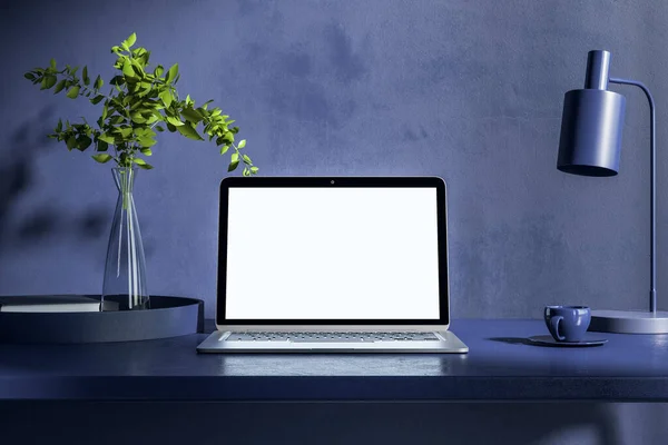 Blank white laptop monitor on dark table with plant in glass transparent vase and black lamp near coffee mug. 3D rendering, mockup