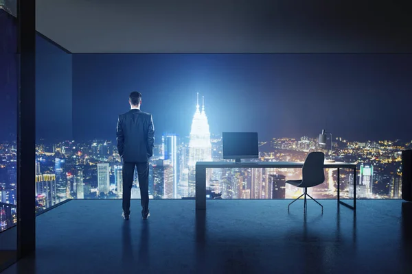 Success concept with businessman back view in high floor stylish office with night city skyscrapers view through mesh walls