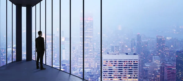 Biznesmen Pustym Biurze Patrząc Przez Okno Panoramiczne Jasnym Centrum Miasta — Zdjęcie stockowe