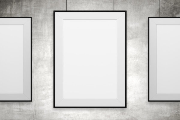 Three blank frames hanging on gray background