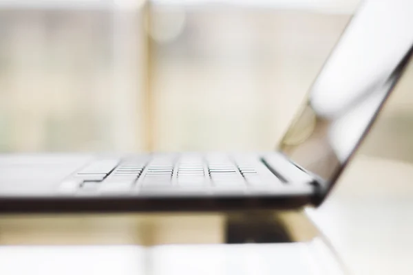 Modern laptop on a glass table, shallow depth of field — Stock Photo, Image