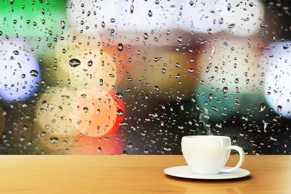 Xícara de café perto da janela com gotas de chuva — Fotografia de Stock