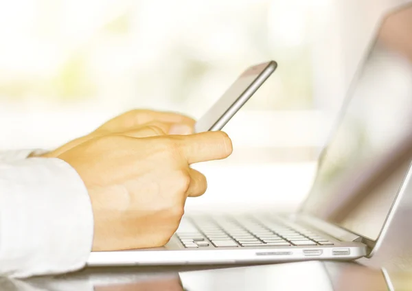 Businessman typing on cellphone and laptop — Stockfoto