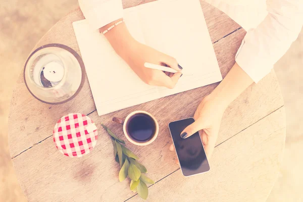 Girl writes in  notebook with cell phone — Stock Photo, Image