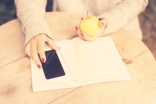 Mädchen mit Handy, Tagebuch und Apfel — Stockfoto