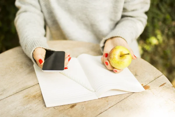 Fille avec téléphone portable, journal intime et pomme — Photo