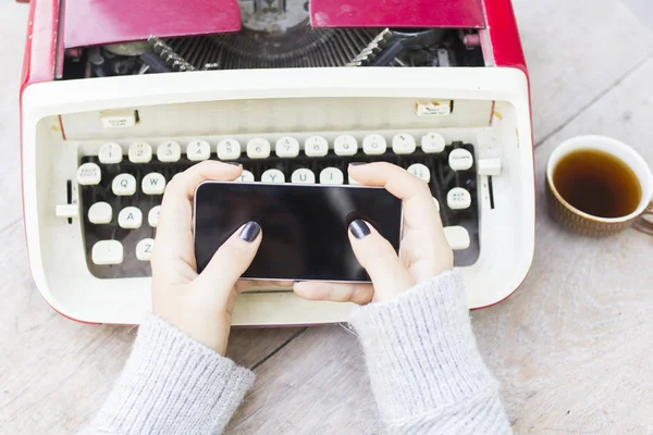 Meisje met mobiele telefoon en schrijfmachine — Stockfoto