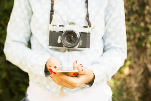 Дівчина з мобільним телефоном і старою камерою — стокове фото