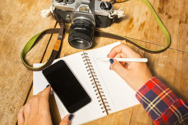 Flicka skriver i anteckningsboken med gamla kameran — Stockfoto