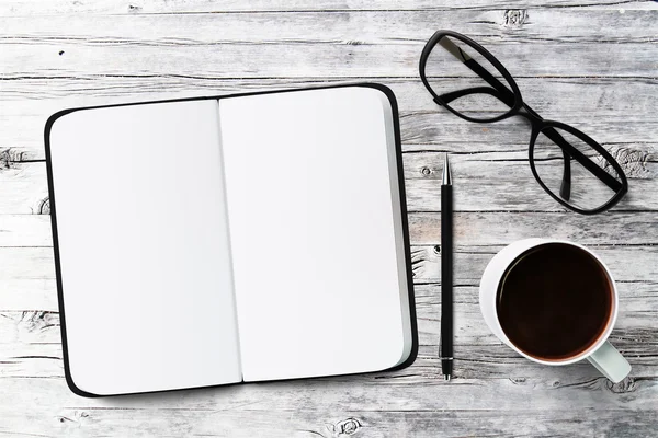 Notebook, kopp kaffe och glasögon — Stockfoto