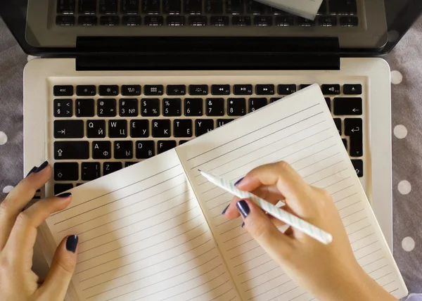 Mädchen schreibt in Notizbuch, mit Laptop — Stockfoto