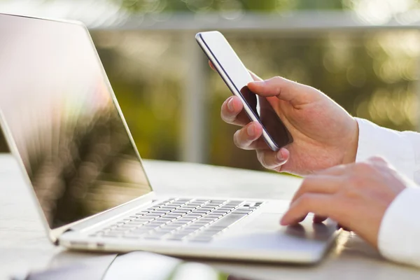 Empresario con celular y portátil — Foto de Stock