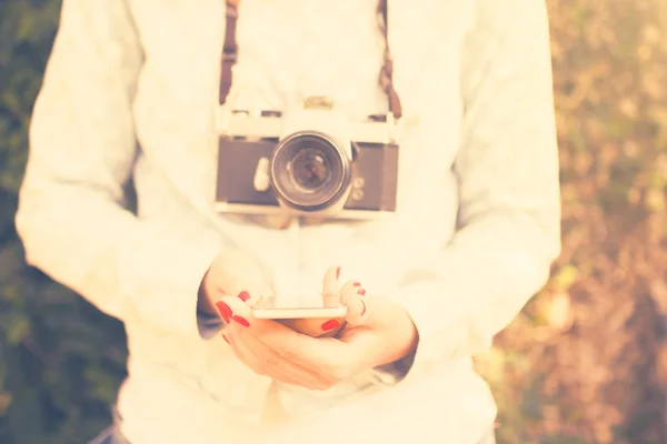 Ragazza con cellulare e vecchia macchina fotografica — Foto Stock