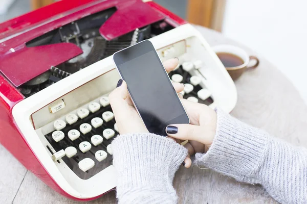 Vrouw met mobiele telefoon en schrijfmachine — Stockfoto