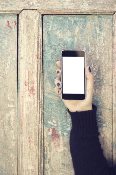 Chica con el teléfono celular en blanco sobre un fondo de madera vintage —  Fotos de Stock