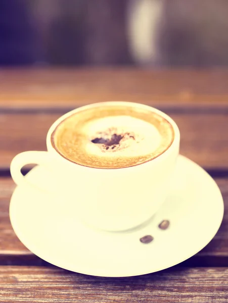 Kopp cappuccino och sauceron ett träbord — Stockfoto
