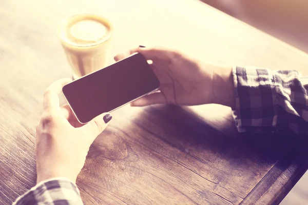 Mädchenhände mit Handy und Kaffeebecher auf Holztisch, Vinta — Stockfoto