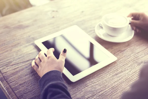 Chica usando tableta digital y una taza de café en una mesa de madera —  Fotos de Stock