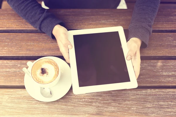 Hombre sosteniendo tableta digital y capuchino en una mesa de madera —  Fotos de Stock