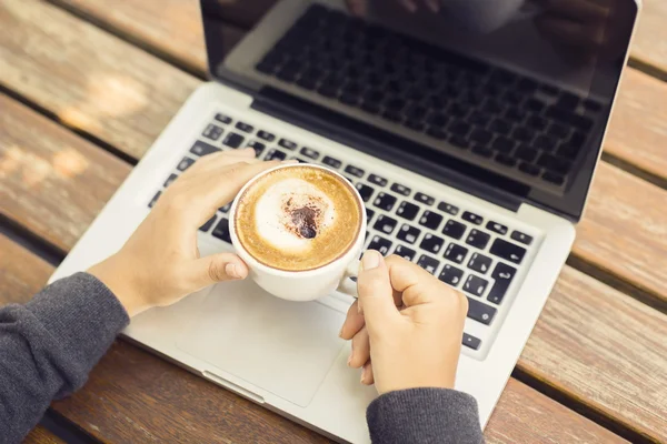 Laptop e cappuccino em uma mesa de madeira — Fotografia de Stock