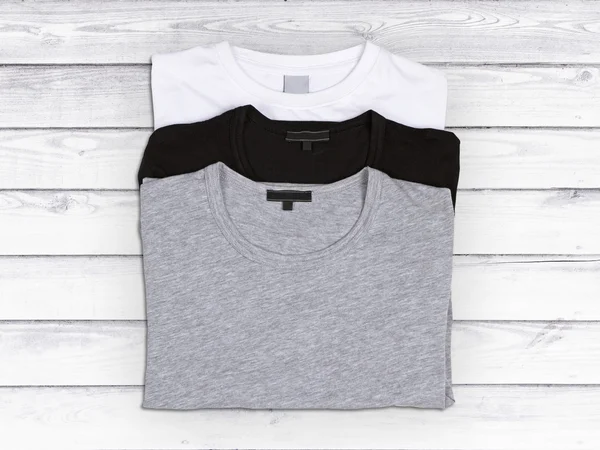 Drei leere T-Shirts auf weißem Holzgrund — Stockfoto