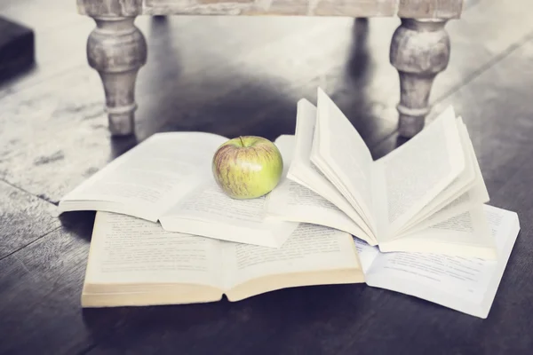 Apple и четыре открытые книги на полу — стоковое фото