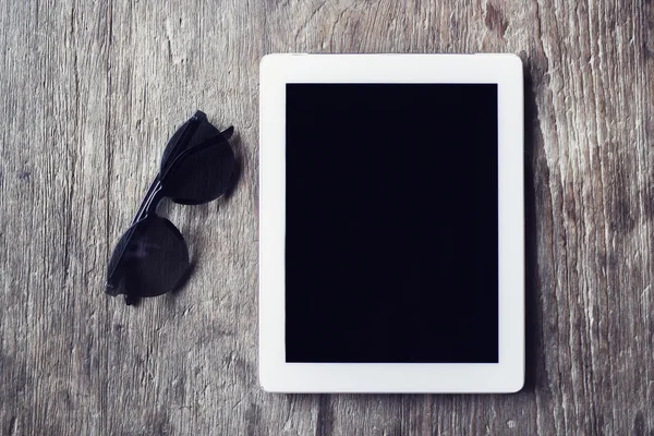 Tableta digital con gafas de sol sobre una mesa de madera —  Fotos de Stock