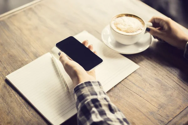 Ragazza mano con smartphone, diario in bianco e una tazza di caffè su un w — Foto Stock