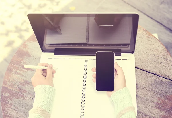 Menina com smartphone, diário em branco com caneta e laptop em um woode — Fotografia de Stock