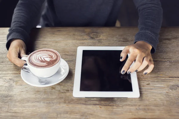 Mains de fille avec tablette numérique et tasse de café sur une languette en bois — Photo