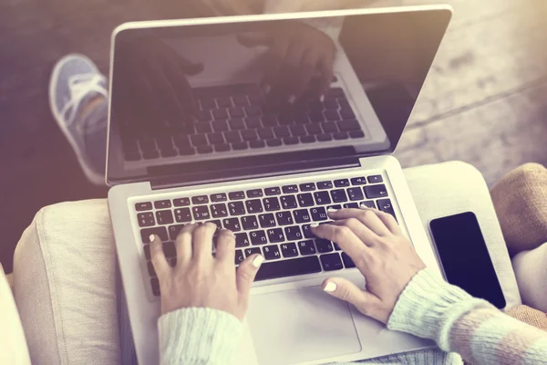 Mãos de menina digitando no laptop e smartphone, efeito de foto vintage — Fotografia de Stock