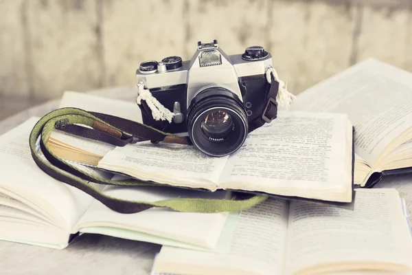 Starý fotoaparát a mnoho otevřených knih na dřevěný stůl — Stock fotografie